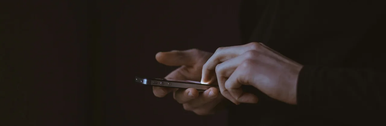 Manos usando un teléfono casi a oscuras